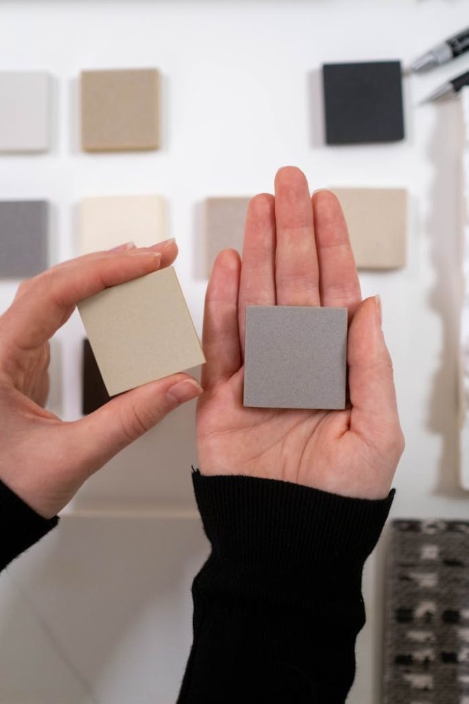 Close-up of hands holding color swatches in a design setting, material showcasing selection and creativity.